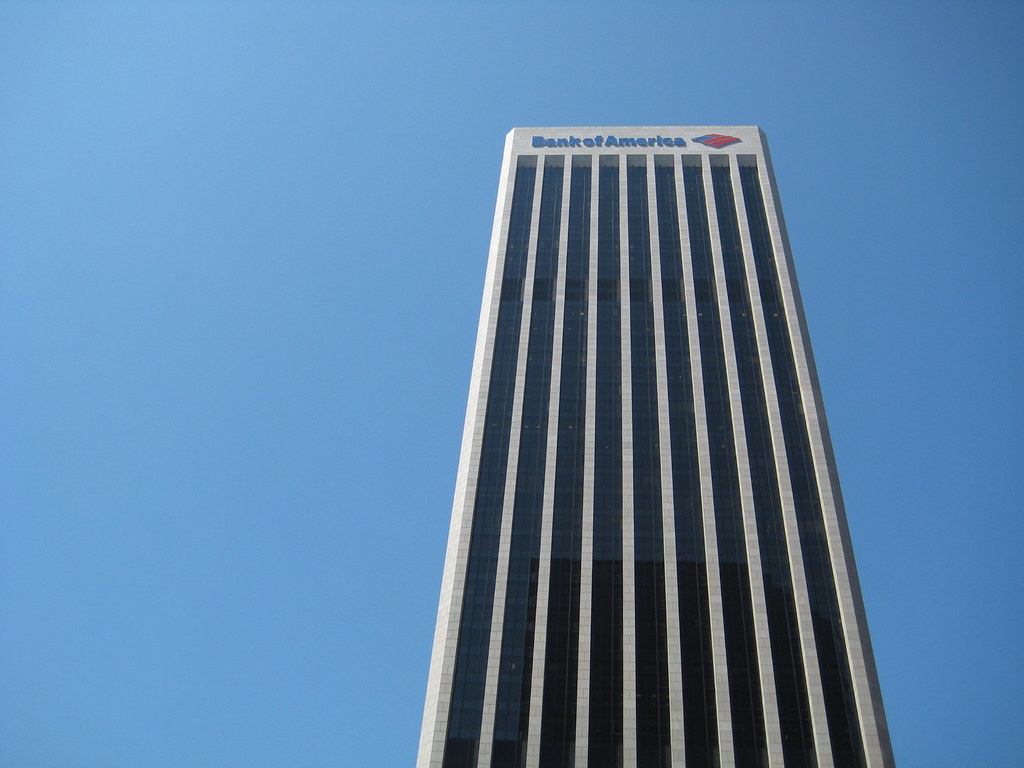 Tall Bank of America building with the logo visible at the top against a clear blue sky.