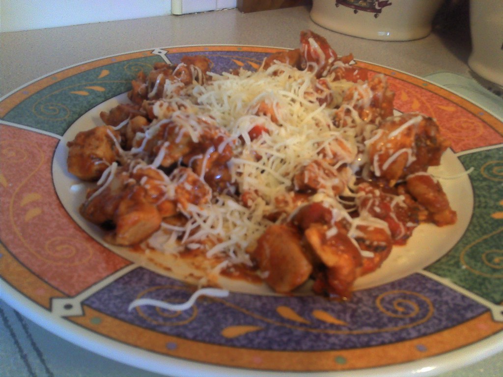 Plate with cooked skillet dinner topped with shredded cheese on a colorful patterned plate.