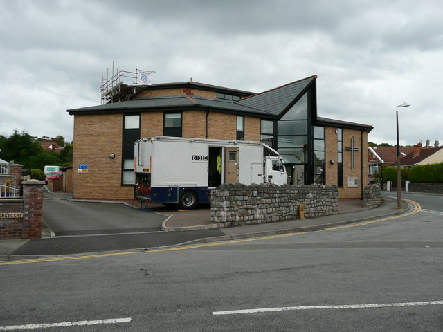 BBC outside broadcast truck parked outside a modern brick church building on a cloudy day