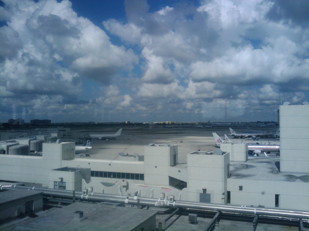 Wide view of Miami airport runway and terminal under a cloudy sky