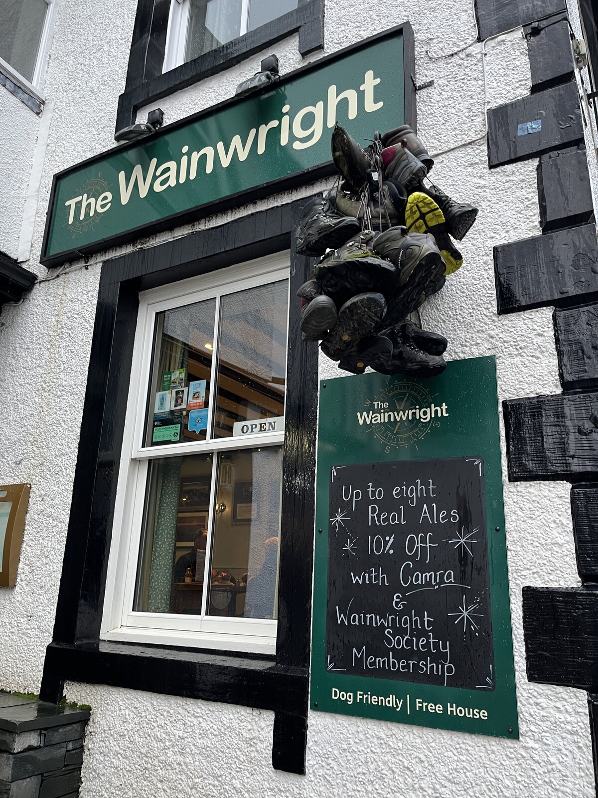 Exterior view of The Wainwright Pub with a window, signage, and a display of hanging boots.