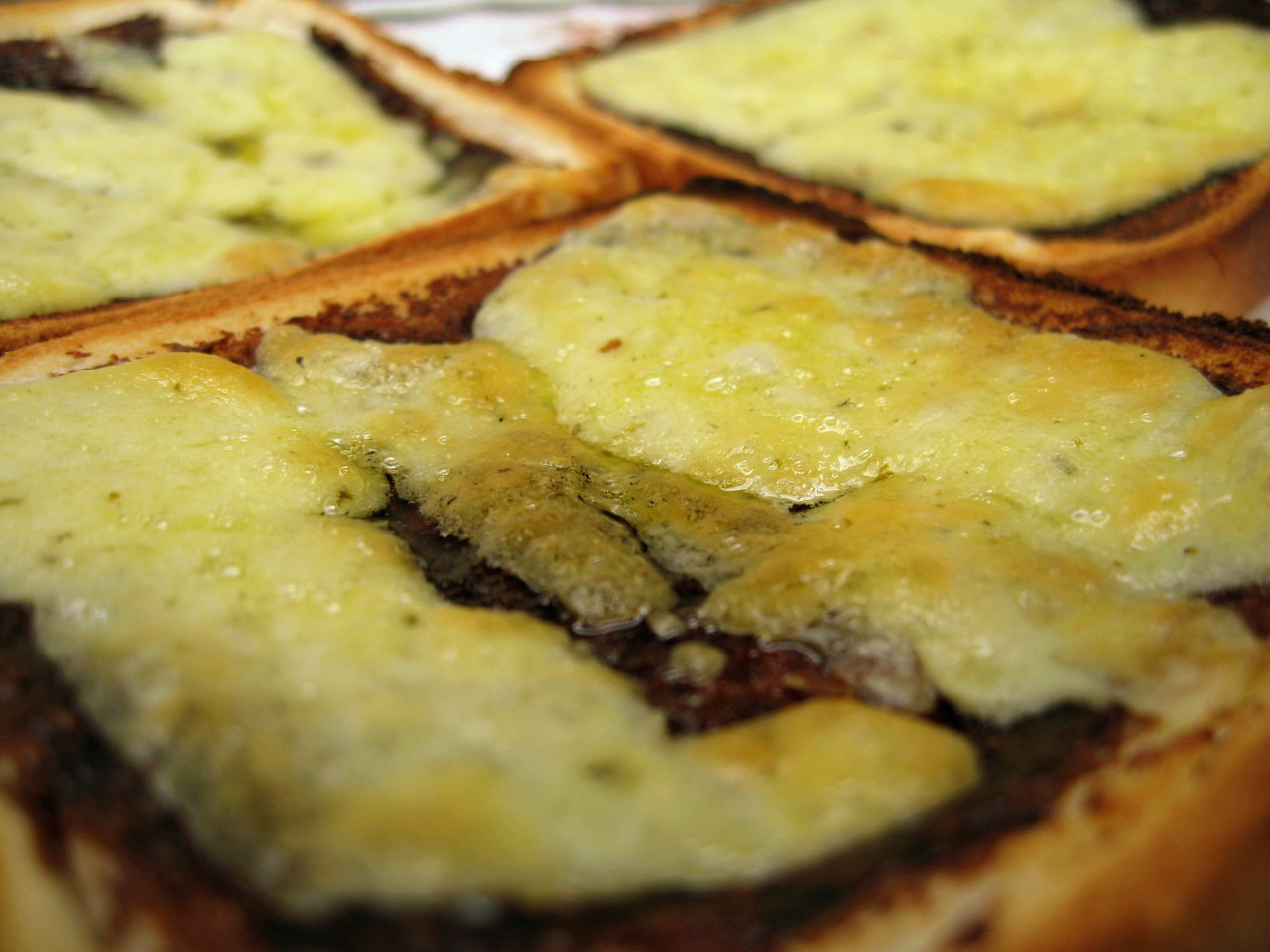 Close-up of toasted bread with Vegemite and melted cheddar cheese on top.