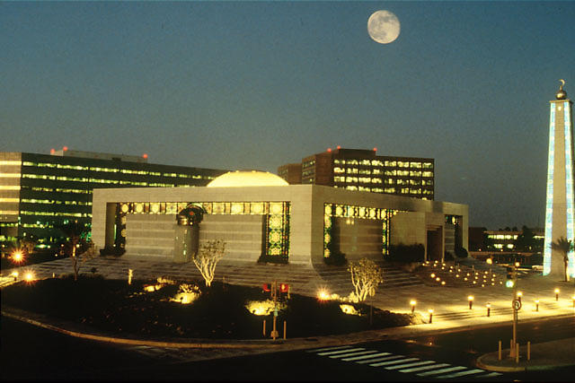 View of Saudi Aramco headquarters and surrounding office buildings at dusk with the moon in the sky.
