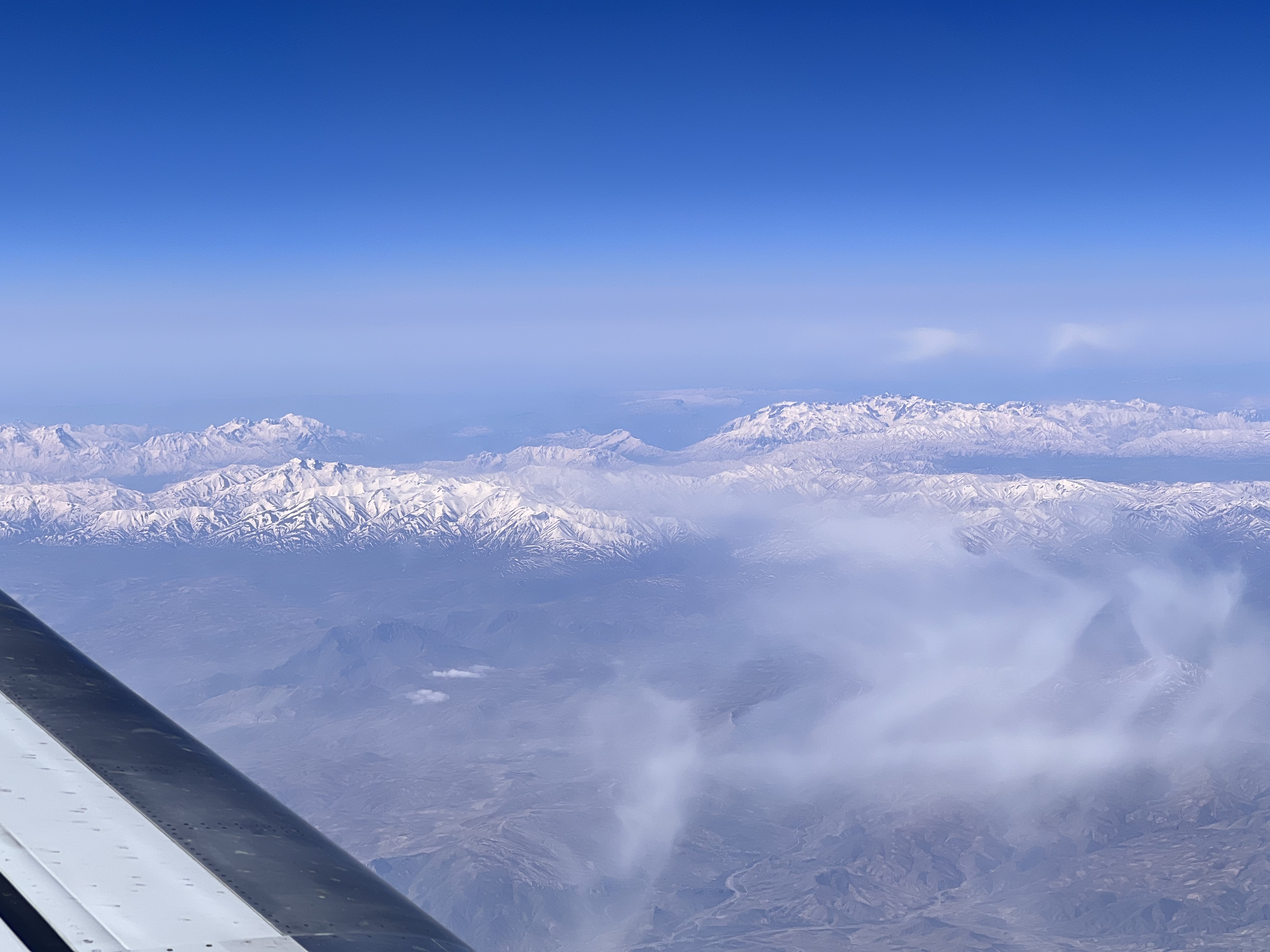 View of snow-covered mountains and landscape over Iran from window of a Flydubai aircraft wing