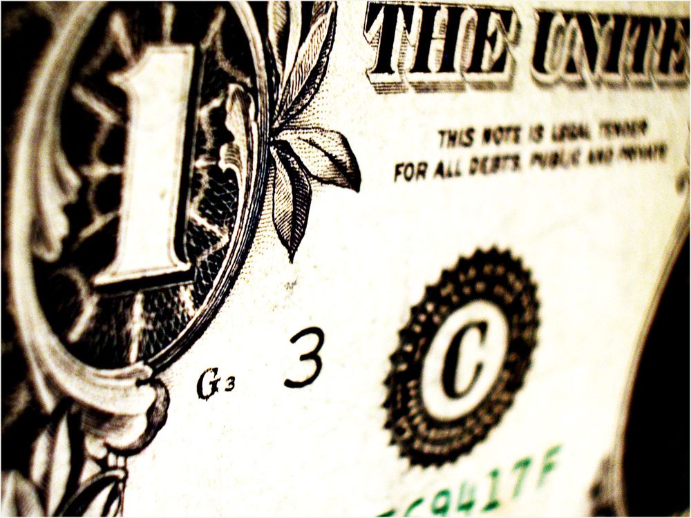 Close-up photograph of a section of a dollar bill showing detail in the design and text