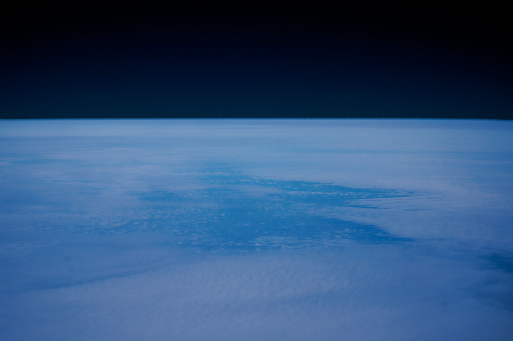 View of Earth from space showing cloud cover with the dark expanse of space above.