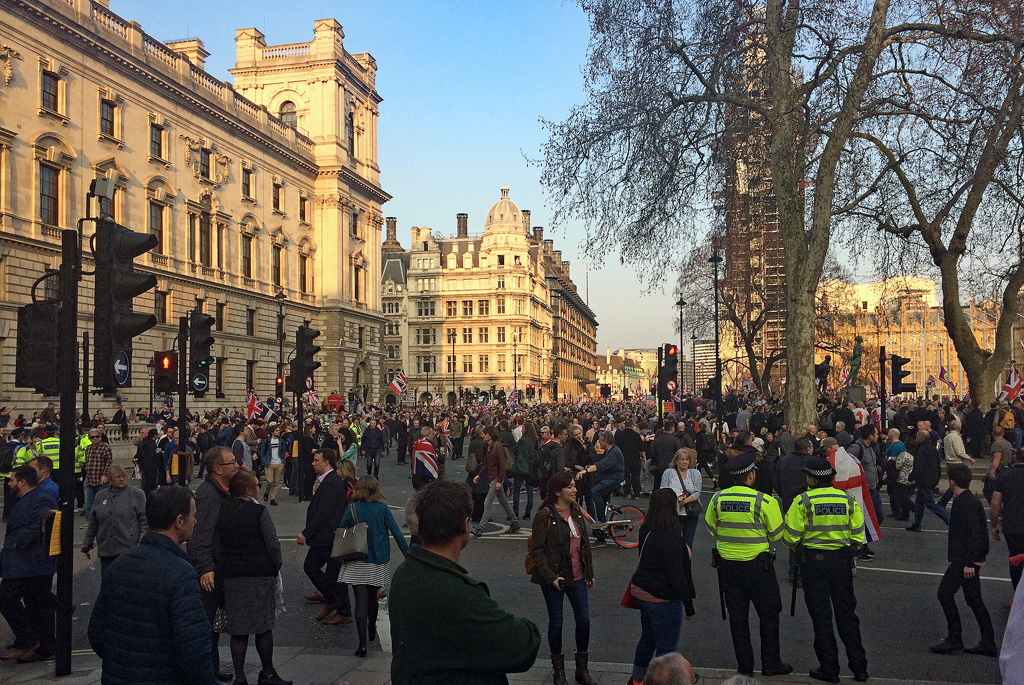 Crowd of people with UK flags and police near UK parliament buildings during a Brexit demonstration.