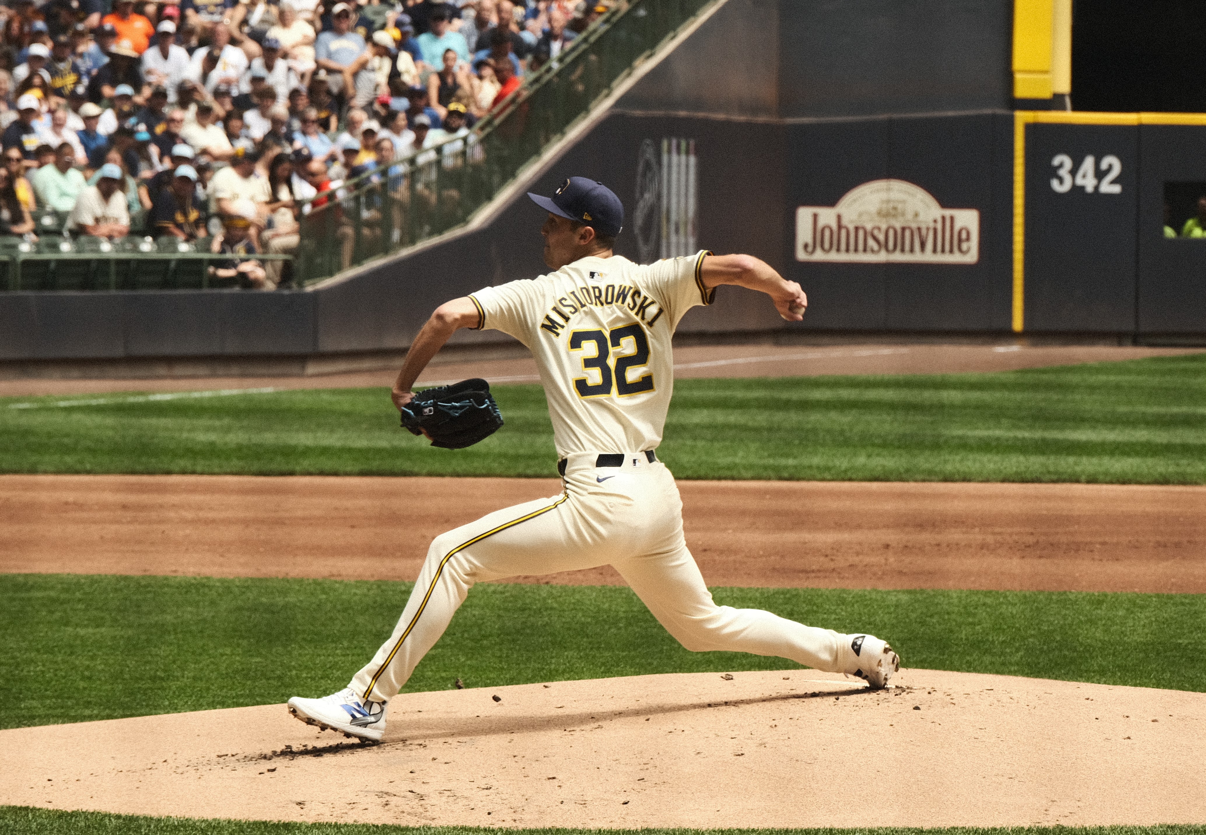 Baseball pitcher Jacob Misiorowski in white uniform throwing a pitch on a mound in a stadium with crowd in the background.