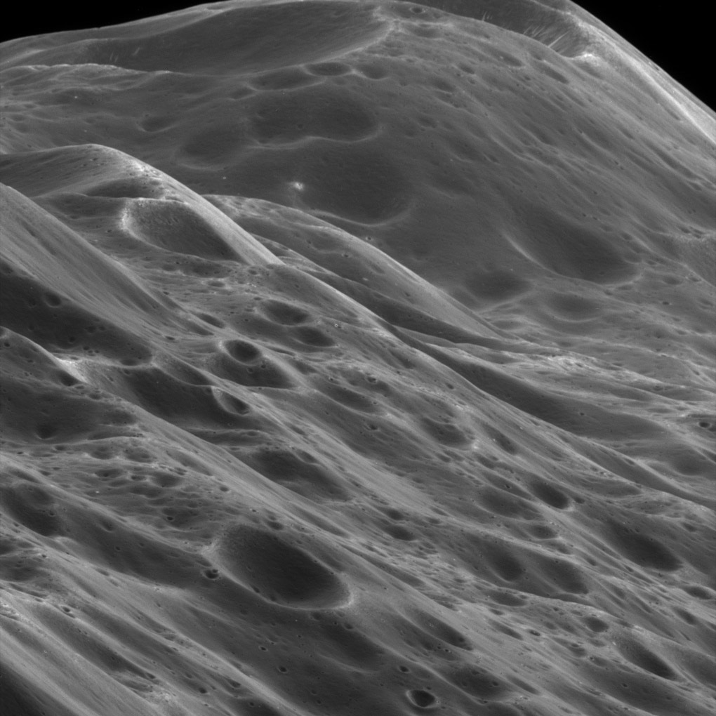 Close-up black and white photograph of Iapetus moon showing its mountainous terrain with many craters and ridges
