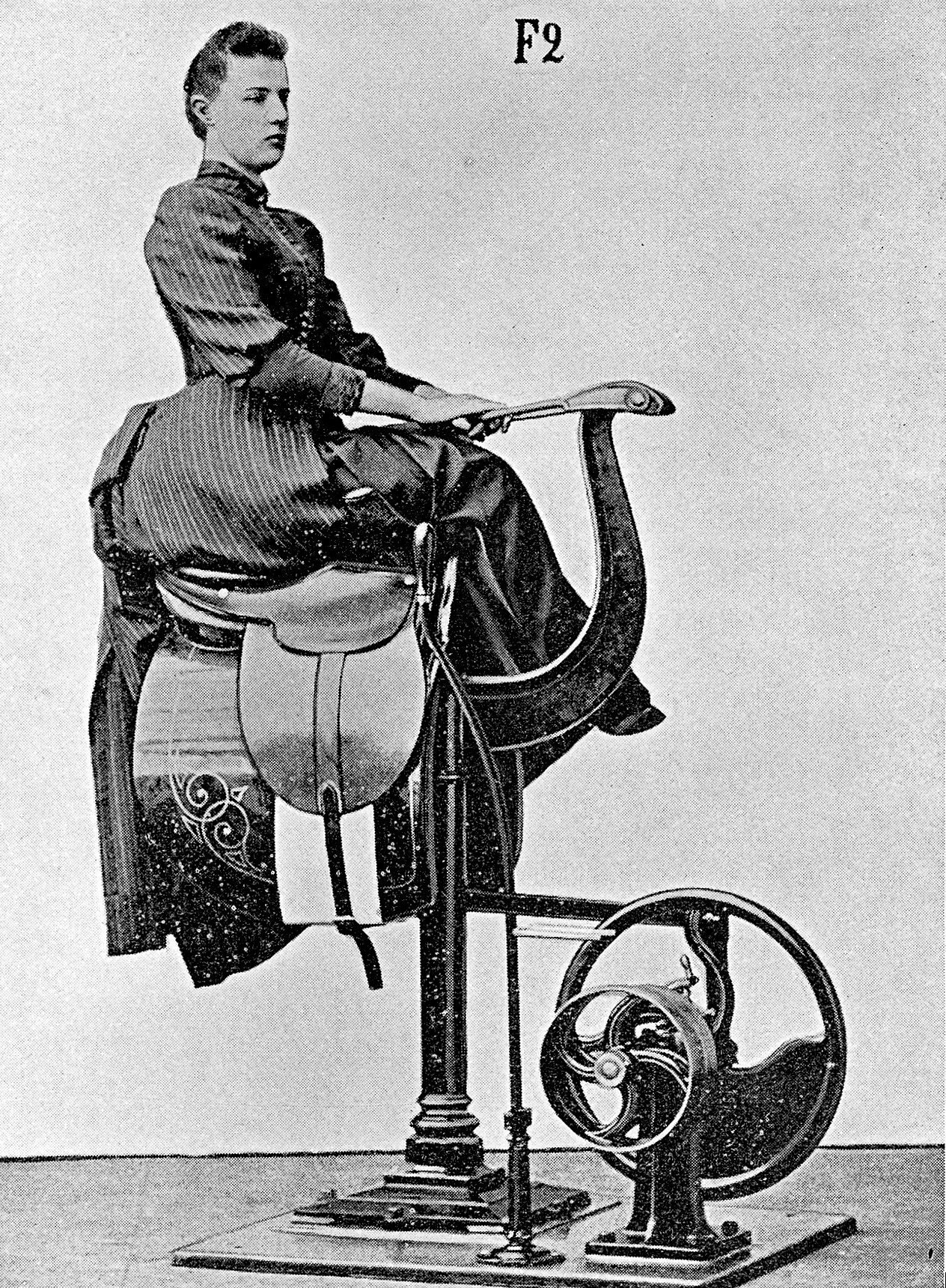 Black and white photograph of a woman sitting sideways on a saddle-like vibration machine with mechanical parts beneath.