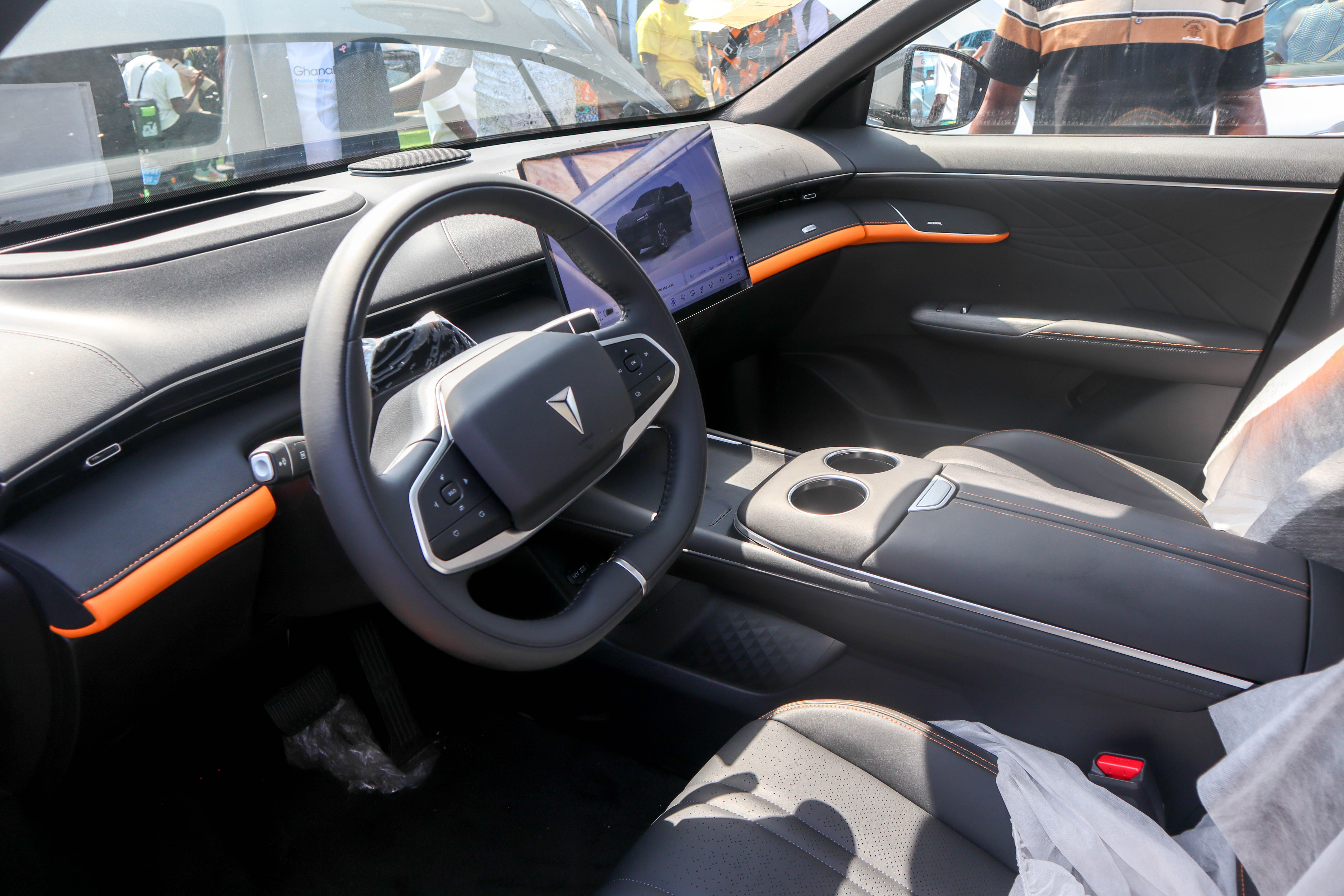 Interior of an electric vehicle showing the steering wheel, dashboard, touchscreen display, and seating
