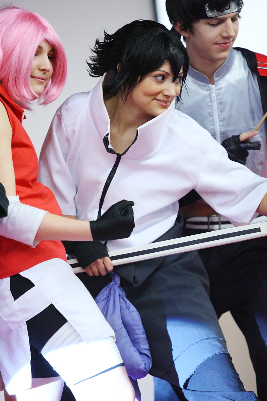 People dressed in Naruto cosplay costumes at Paris Manga event, including characters with pink and black hair and ninja headbands.
