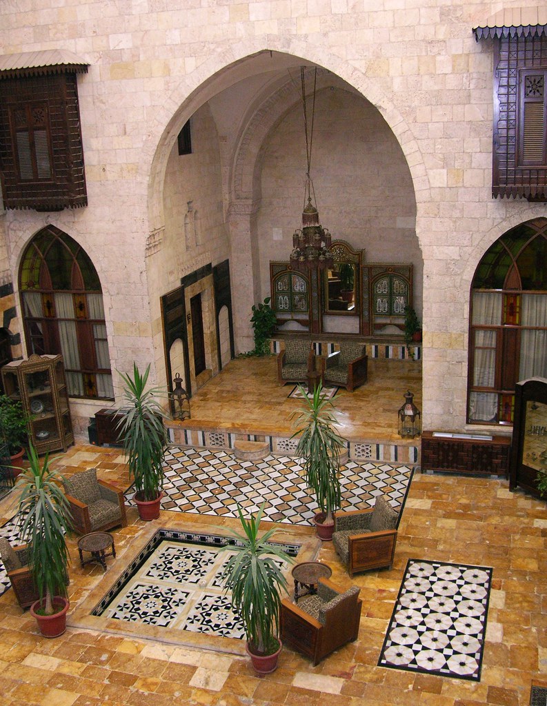 Lobby area of Dar Zamaria Hotel in Aleppo, Syria, featuring traditional architecture, plants, and seating.